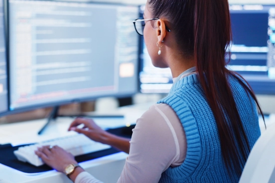 A photograph of a person sat in front of a computer screen typing