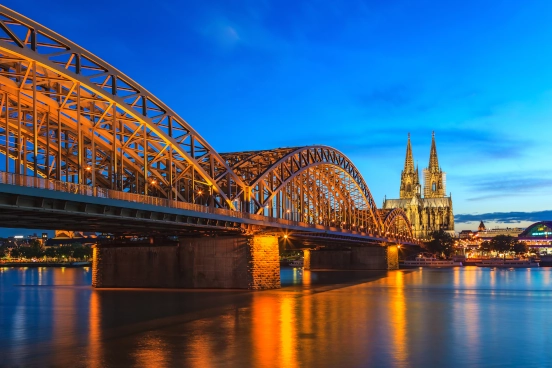 An image at dusk of Cologne's Hohenzollern Bridge and St Peters cathedral in the background.