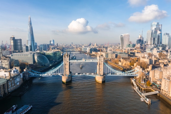 An aerial view of the Thames river with Tower bridge and city building landmarks in the distance