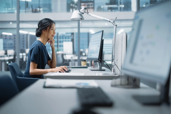 A photograph of a medical professional sat at a desk operating a personal computer.